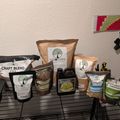 A collection of gardening supplies and plant nutrients from BuildASoil.com arranged on a wire shelf, including bags of soil amendments, liquid fertilizers, and other growing products.