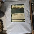 A white bag of BuildASoil brand flower top dress soil amendment sitting on a wooden surface