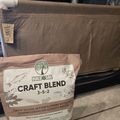 A bag of BuildASoil Craft Blend fertilizer (3-5-2) sitting on a concrete surface next to fabric planting beds in what appears to be a greenhouse or growing area