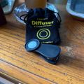 A black clip-on camera lens diffuser and cosine corrector with its storage pouch on a wooden table