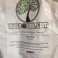 Package of rice hulls from BuildASoil.com organic garden supply company, featuring a tree logo and product information on a clear plastic bag
