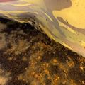 A yellow fabric or tarp covering dark soil with scattered debris and small particles visible underneath